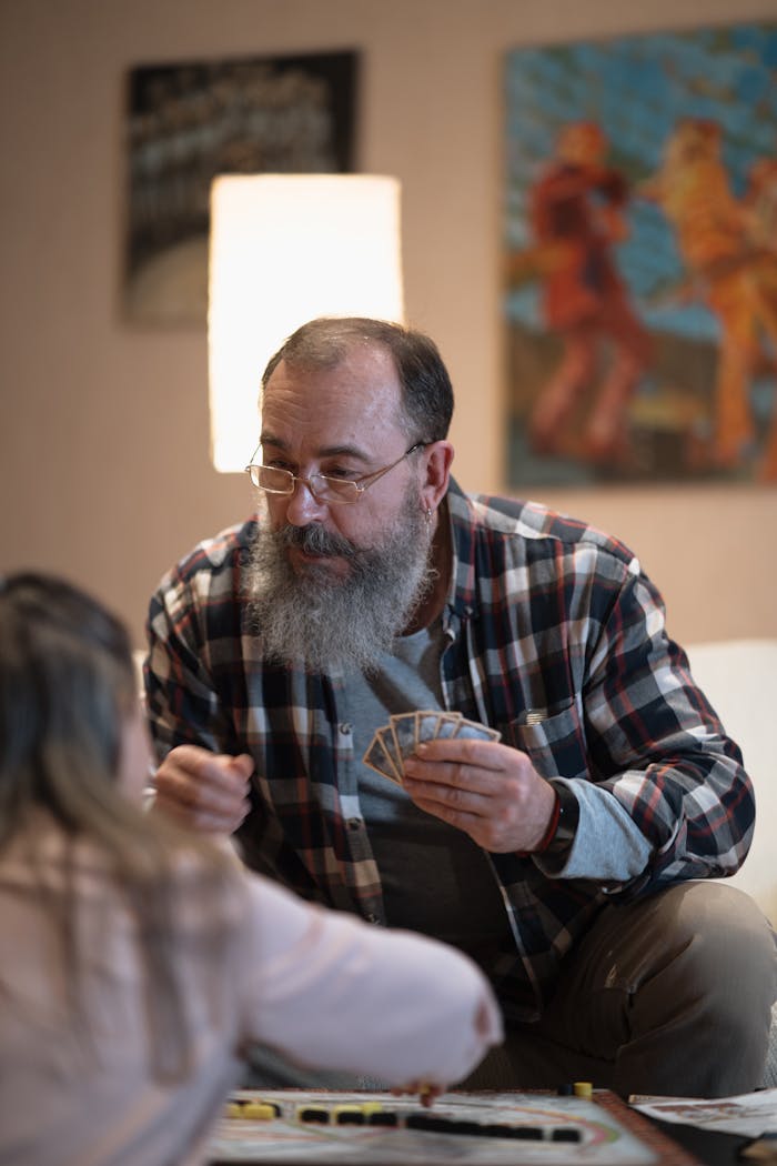 A joyful moment of a senior man playing a board game with his granddaughter at home.